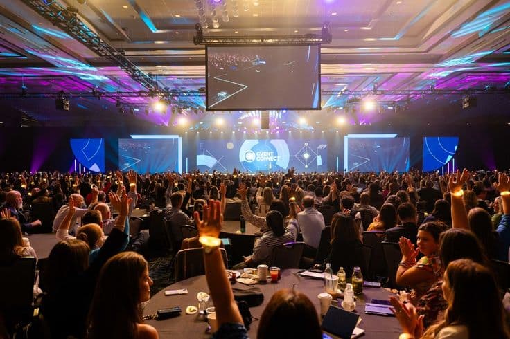Audience cheering at a large conference stage